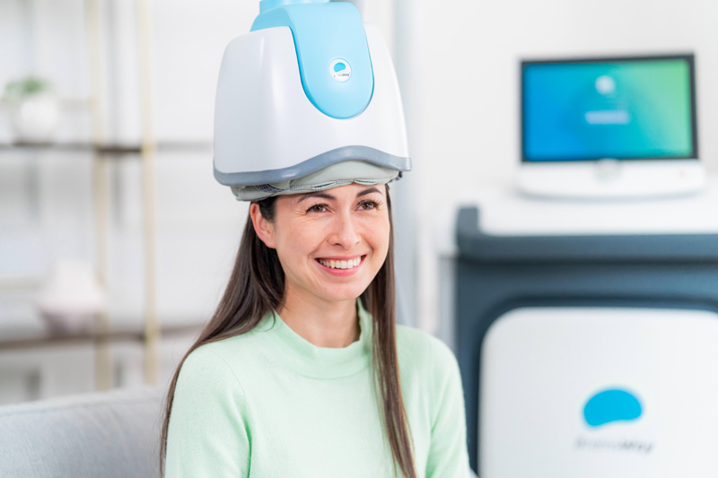 woman smiling while doing tms therapy