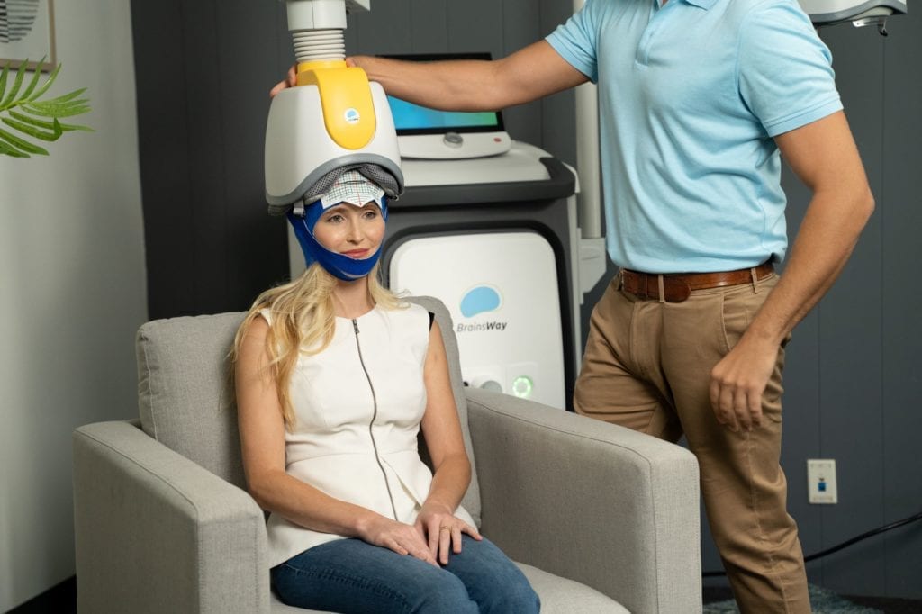 Split image of two patients undergoing TMS treatment. The first in a more relaxed position using the Brainsway  and the second in a more rigid position using a traditional TMS device.